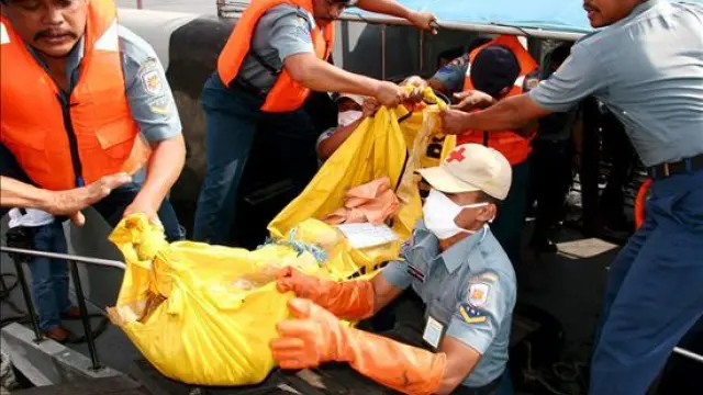 Efectivos de rescate transportan un cadáver en el puerto indonesio de Surabaya.