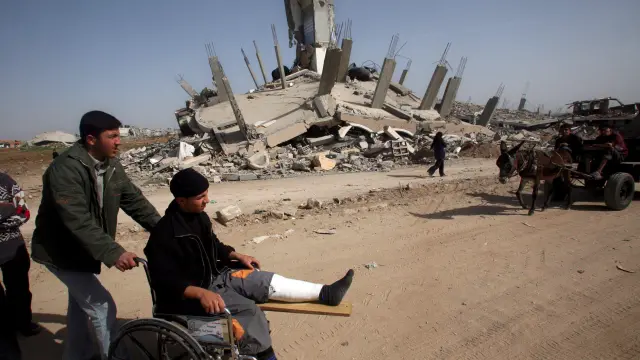 Un herido, en silla de ruedas, visita una zona de Gaza destrozada por las bombas israelíes