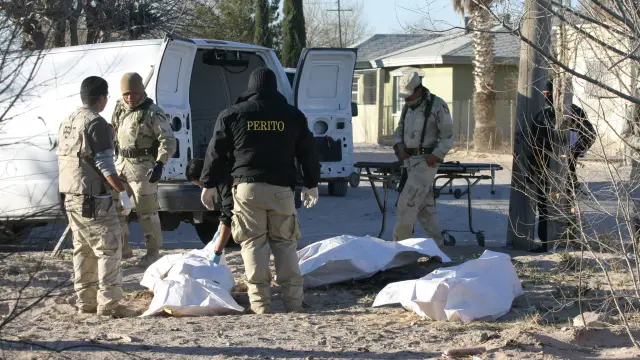 Peritos forenses y miembros del Ejército mexicano realizan el levantamiento de los cadáveres