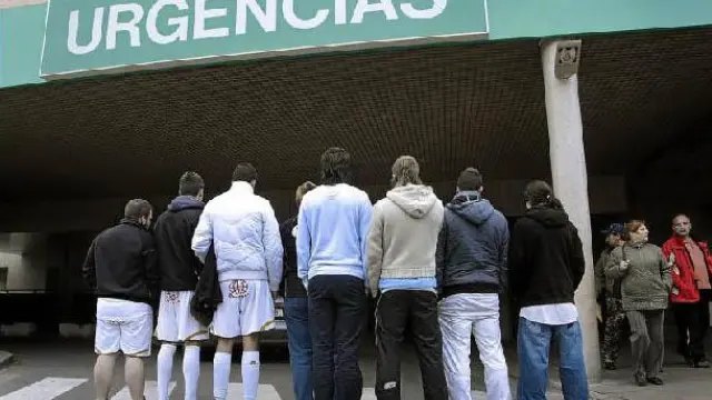 Alineación de jugadores del Bar Yuste, algunes vestidos de futbolistas, en la puerta de Urgencias del hospital Miguel Servet.