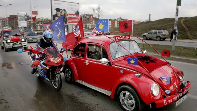 Ciudadanos albanokosovares circulan con sus vehículos decorados con banderas de Kosovo y Estados Unidos