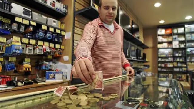 Nacho Benajes, propietario de una tienda de electrónica del Centro Histórico, muestra los billetes y monedas de pesetas que ha aceptado