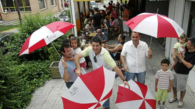 Peñistas de El Disfrute, tras recibir los vales de comidas y bebidas junto con el regalo sorpresa de esta Vaquilla, un paraguas rojiblanco
