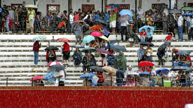 La gente se apresuró a sacar los paraguas y a protegerse del agua en los tendidos.