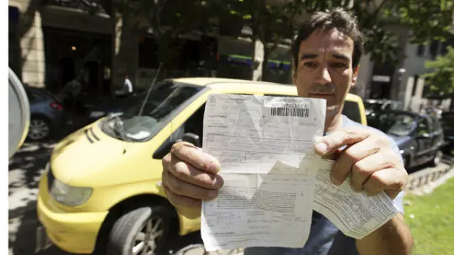 Andrés Espiño, junto a otro vehículo de su empresa, muestra la multa que le pusieron el viernes.