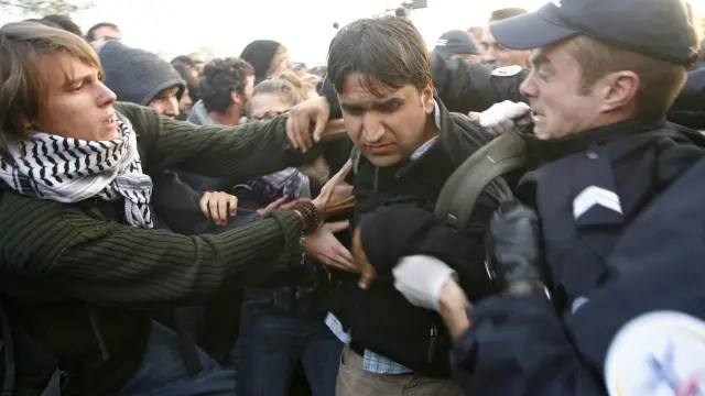 Policias detienen a un inmigrante ilegal durante la operación de desmantelamiento en un campamento de inmigrantes