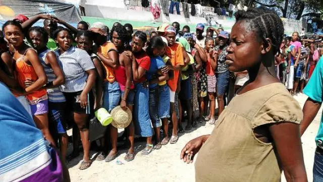 Una embarazada, frente a las mujeres que esperan la distribución de agua, en Puerto Príncipe