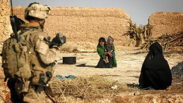 Un soldado estadounidense observa a dos mujeres afganas, una con un niño en Afganistán