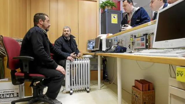 Dos oficiales se calientan con un calefactor en la recepción del centro cívico.