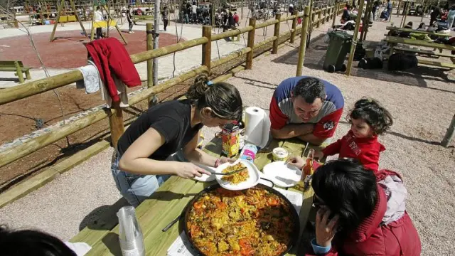 Un grupo de excursionistas se dispone a comer una paella en el nuevo parque de Fuentecerrada, con todas las mesas ocupadas.