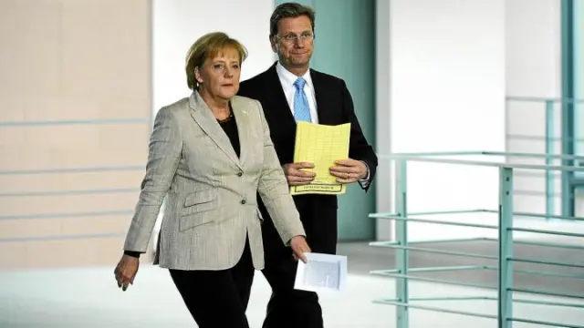 Angela Merkel, acompañada por el ministro alemán de Exteriores, camino de una rueda de prensa, ayer en Berlín.