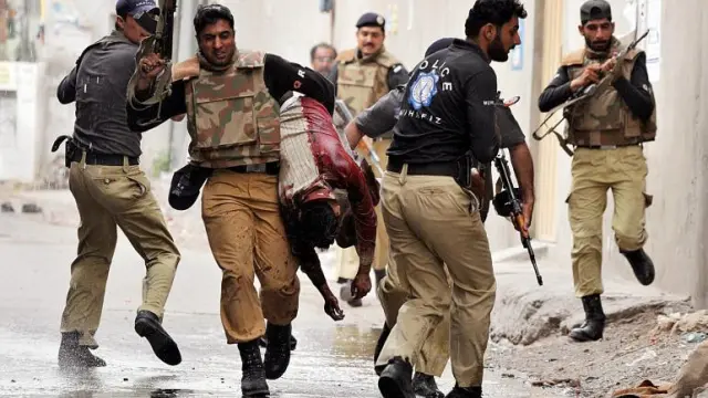 Agentes pakistaníes protegen una de las mezquitas atacadas en Lahore y llevan a un herido, ayer.