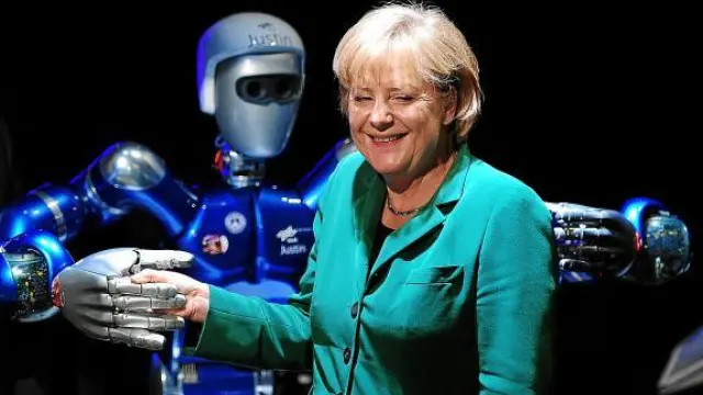 Merkel sonríe al dar la mano al robot 'Justin' durante la Feria Aeronáutica de Berlín, ayer.
