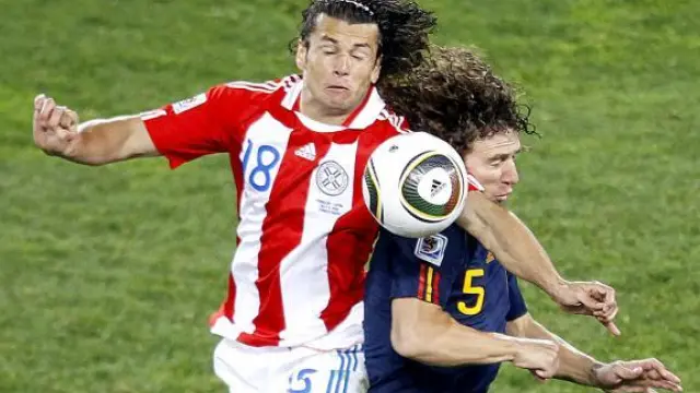 Puyol salta con el jugador paraguayo Nelson Valdez durante el partido de anoche.