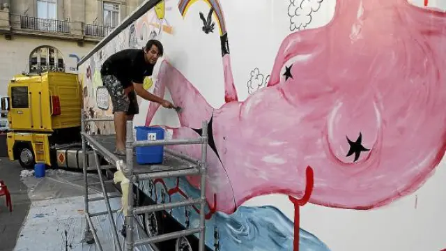 El artista Leto da las últimas pinceladas a su pintura mural en el lateral del remolque.