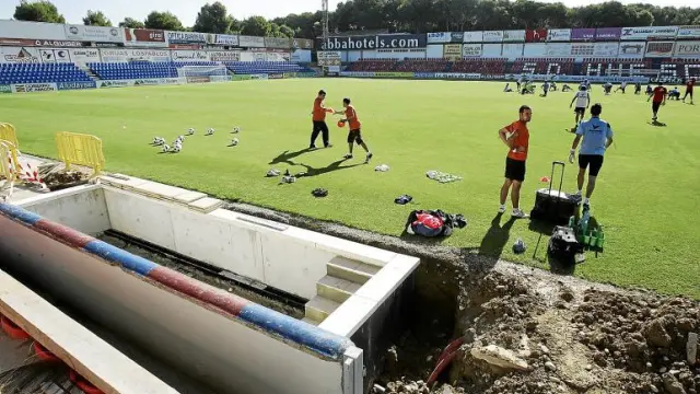 Los jugadores del Huesca, durante el entrenamiento de ayer en El Alcoraz. En primer término, las obras en los banquillos.