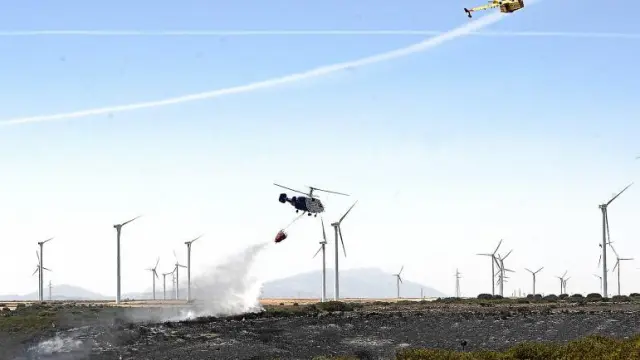Un helicóptero echa agua sobre las llamas mientras un hidroavión sobrevuela la zona del incendio.