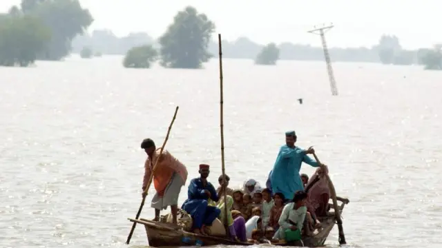 Varias personas se trasladan en una barca por una zona inundada