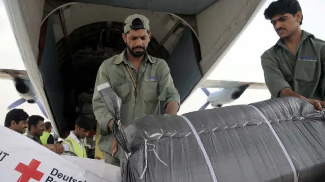 Un equipo de trabajadores descarga ayuda humanitaria donada por la Cruz Roja