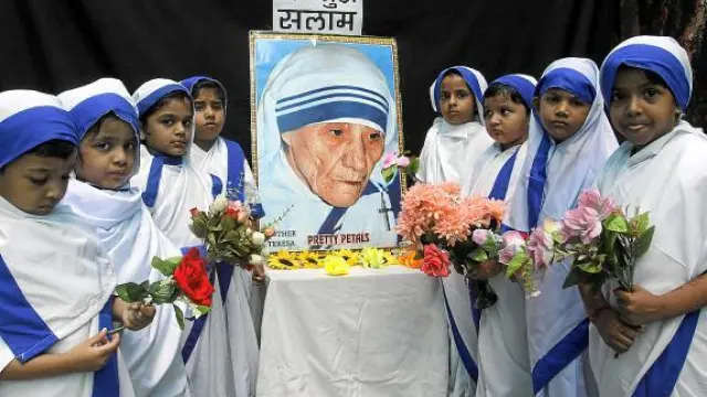 Niñas vestidas como Misioneras de la Caridad realizan una ofrenda floral en India, ayer.