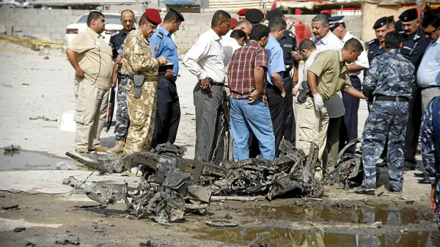 Miembros de la policía irquí inspeccionan el lugar donde explotó ayer un coche bomba en Basra, al sur de Iraq.