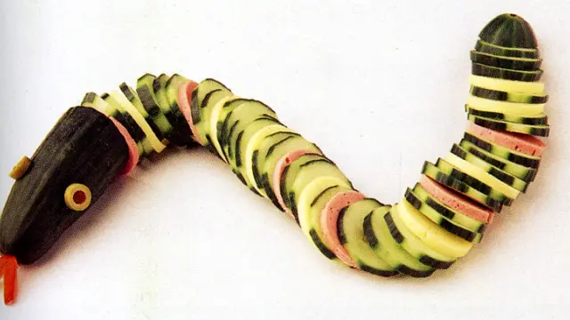 Una serpiente hecha con rodajas de pepino, mortadela y aceitunas para los ojos