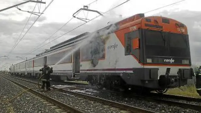 Un bombero sofoca el incendio declarado en la máquina del tren.