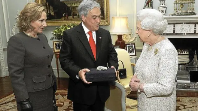 Isabel II recibe una piedra del pozo San José de manos de Piñera y su mujer, ayer en Londres.