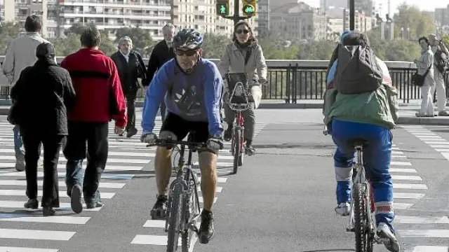 Varios ciclistas, en un paso de cebra con semáforo junto al puente de Santiago.