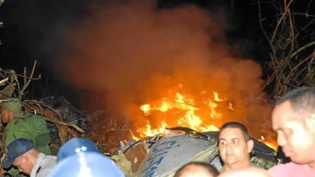 Varias personas tratan de buscar supervivientes en el avión, en llamas, que se estrelló en Cuba.