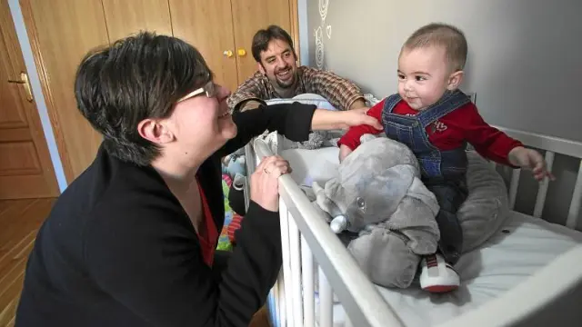 Juan, el bebé de cinco meses risueño y simpático, posa en su dormitorio junto a sus padres y con su peluche favorito.