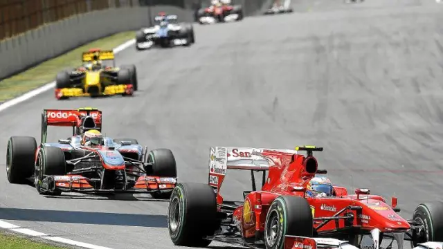 El piloto español Fernando Alonso (Ferrari), supera a su rival Lewis Hamilton (McLaren) durante el Gran Premio de Brasil.