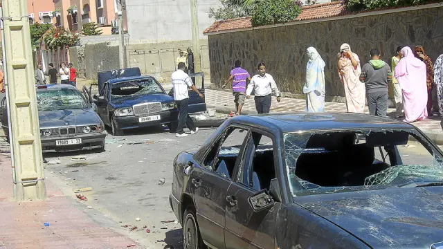 Varios saharauis observan tres coches con los cristales rotos, ayer en una calle de El Aaiún