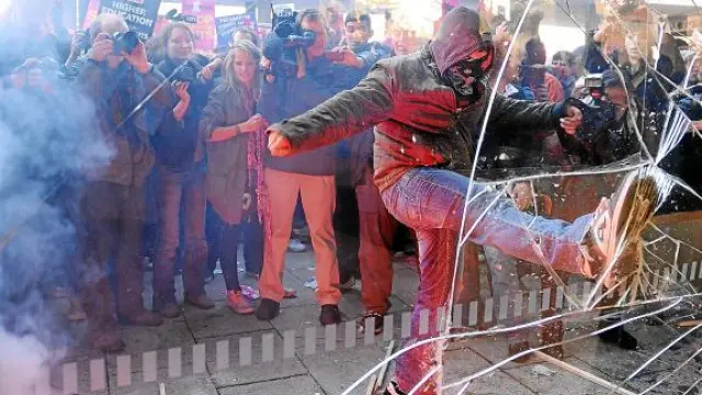 Uno de los manifestantes golpea con la pierna el cristal de la sede del partido.