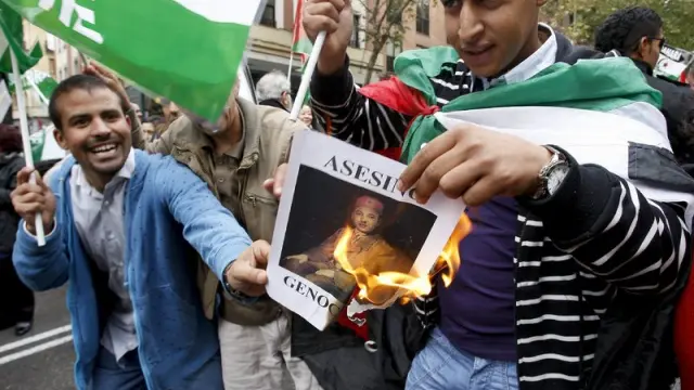 Dos ciudadanos marroquíes queman una fotografía del rey de Marruecos, Mohamed VI, durante la manifestación organizada en Madrid
