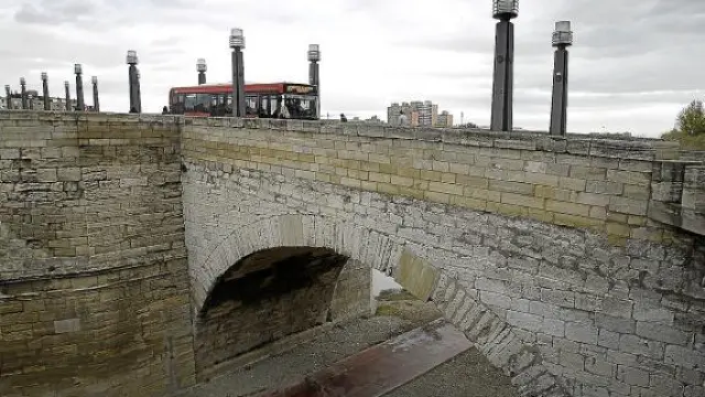 Un autobús atraviesa el puente sobre la arcada dañada por las grietas.