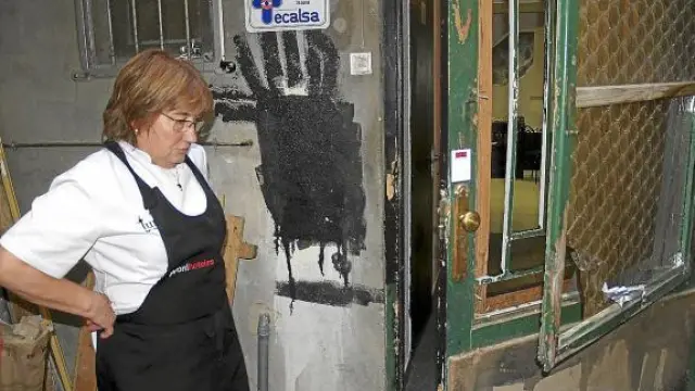 Lourdes Escartín, dueña del bar, observa los desperfectos en la puerta forzada por los cacos.