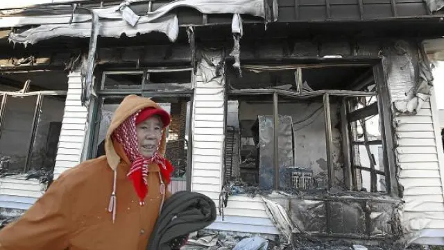 Una mujer pasa junto a una casa destruida en la isla surcoreana de Yeonpyeong, ayer.