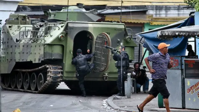 Varios policías prestan guardia junto a un vehículo de las Fuerzas Armadas en una de las zonas conflictivas de Río de Janeiro