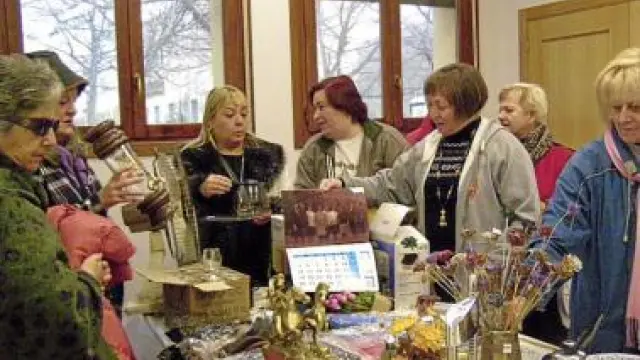 Varias mujeres ojean los objetos a la venta en el rastrillo.