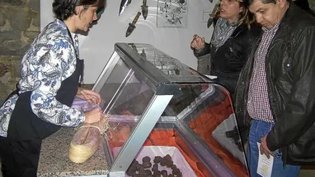 Dos compradores se interesan por las trufas en un mostrador del mercado de Graus.
