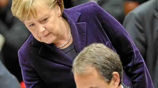 La canciller Angela Merkel se acerca a Zapatero, ayer.
