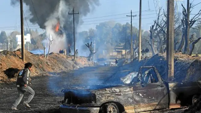 Algunos vecinos observan camiones incendiados tras la explosión en San Martín Texmelucan.