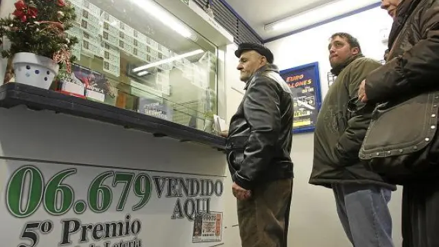 Varios clientes hacen cola ayer en una administración de lotería de Huesca.