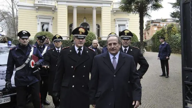 Michale E. Cambanis, ambajador griego, es acompañado por los policías italianos tras hallarrse el artefacto explosivo