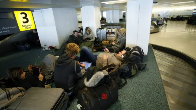 Varios pasajeros acampan mientras esperan para embarcar en el aeropuerto de París.