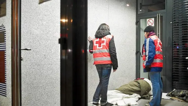 Dos voluntarios de Cruz Roja atienden a una persona sin hogar en Zaragoza.