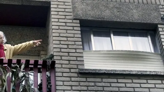 Una mujer señala la fachada ennegrecida de su casa por el fuego
