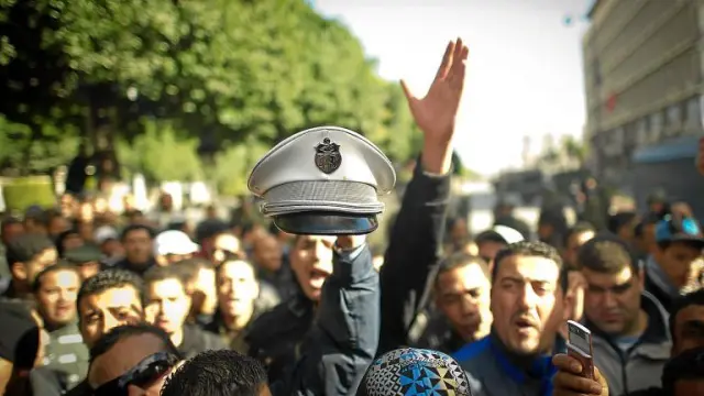 Un manifestante muestra un gorro de la Policía tunecina que ayer se unieron a las protestas.