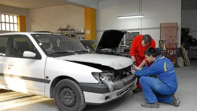 Dos mecánicos de Teruel reparaban ayer los daños de un coche que chocó con un jabalí.